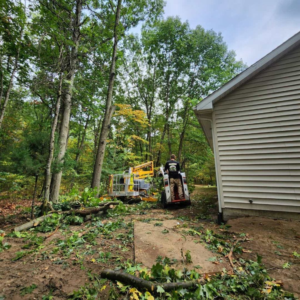 Our crew clears fallen tree branches beside the home using lift and loader.